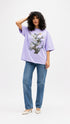 Model wearing HUGFAB lavender snake graphic oversized T-shirt with blue jeans on white background